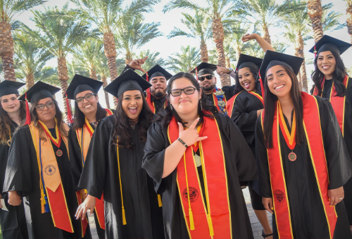 A group of graduates celebrating in their cap and gowns